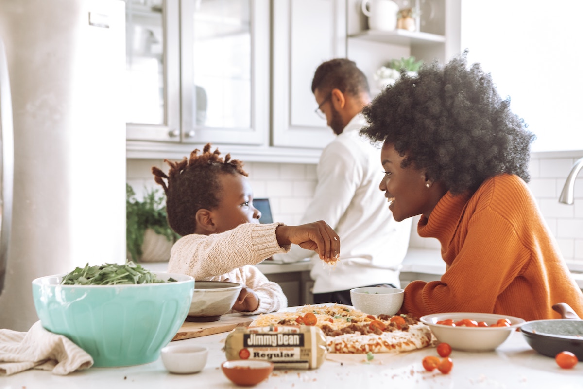 Eine Familie mit einem kleinen Kind macht in der Küche eine Pizza. Die Vorteile der Vermietung von möblierte Wohnungen auf Zeit.