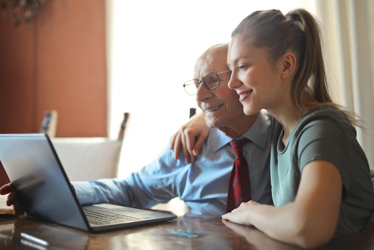 Eine junge Frau zeigt ihrem Grossvater auf einem Laptop with einfach das Vermietungsmanagement mit Wunderflats Plus ist.