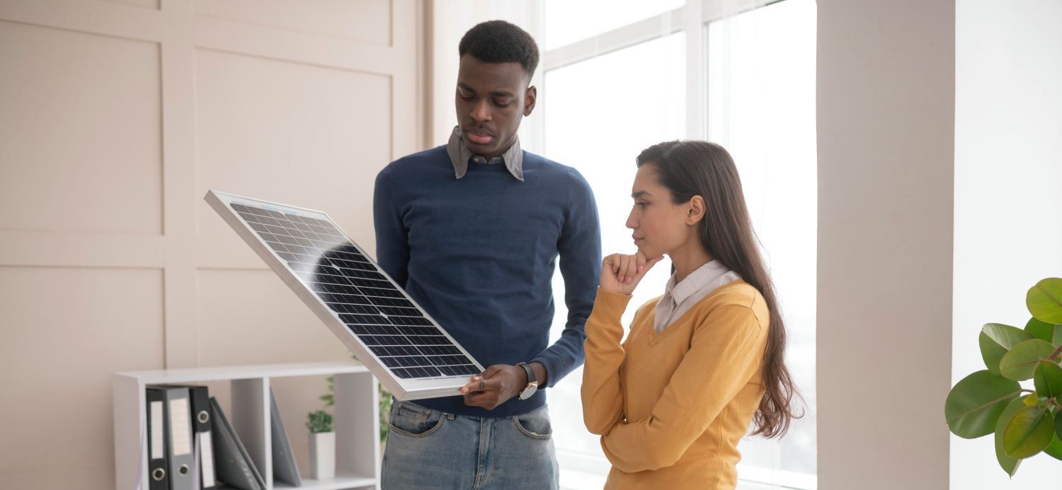 Balkon Solaranlage in der Mietwohnung? Ein Mann und eine Frau betrachten ein Solarmodul, bevor sie es montieren.