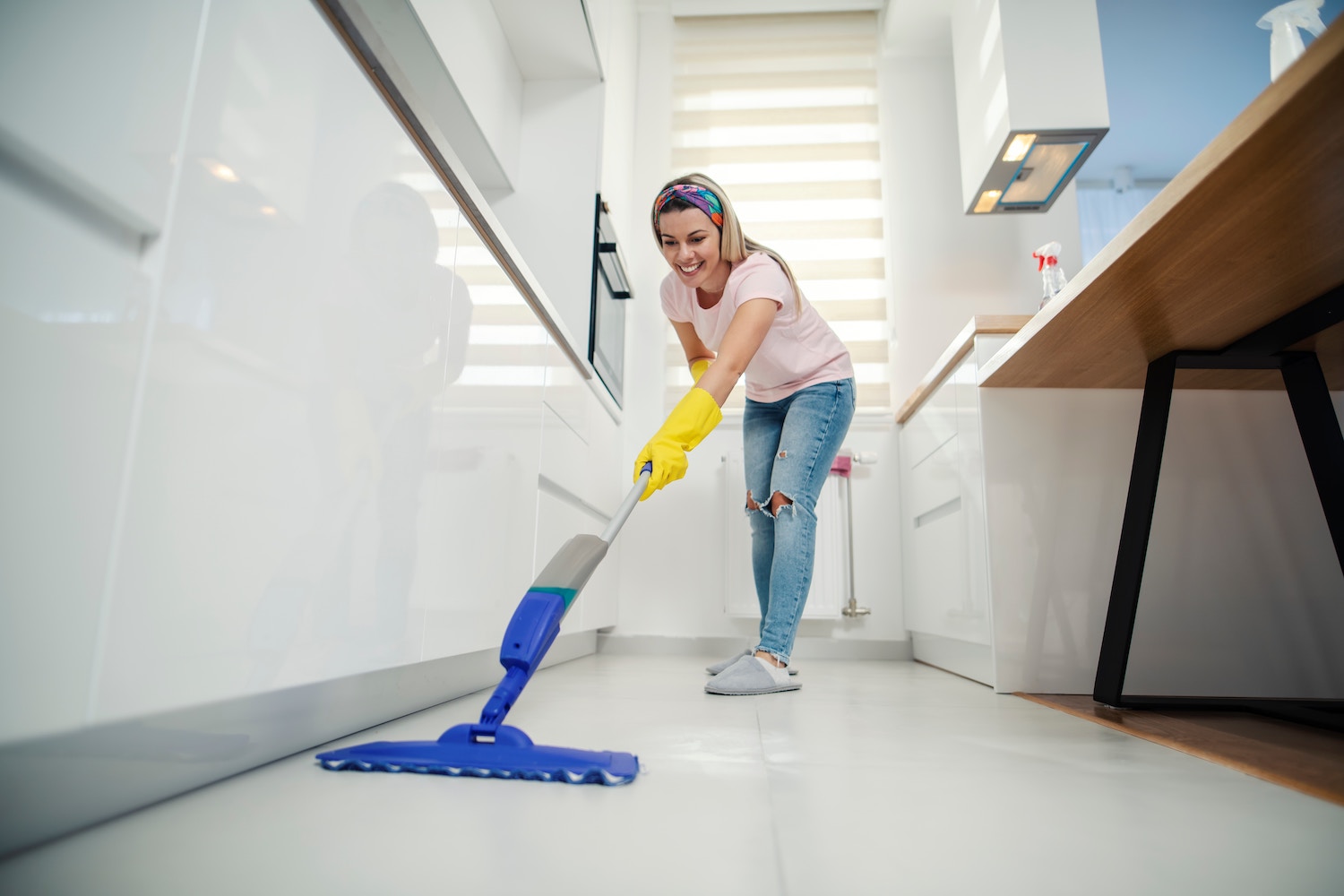 Pflichten bei der Vermietung eines Serviced Apartments. Eine junge Frau wischt den Küchenboden.