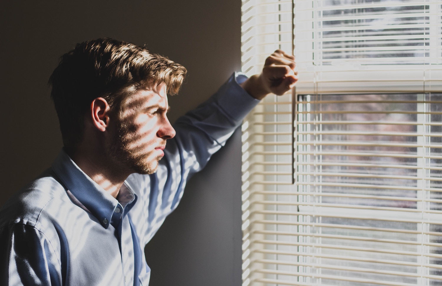 Hausratversicherung als Vermieter: ein Mann schaut aus dem Fenster seiner Wohnung
